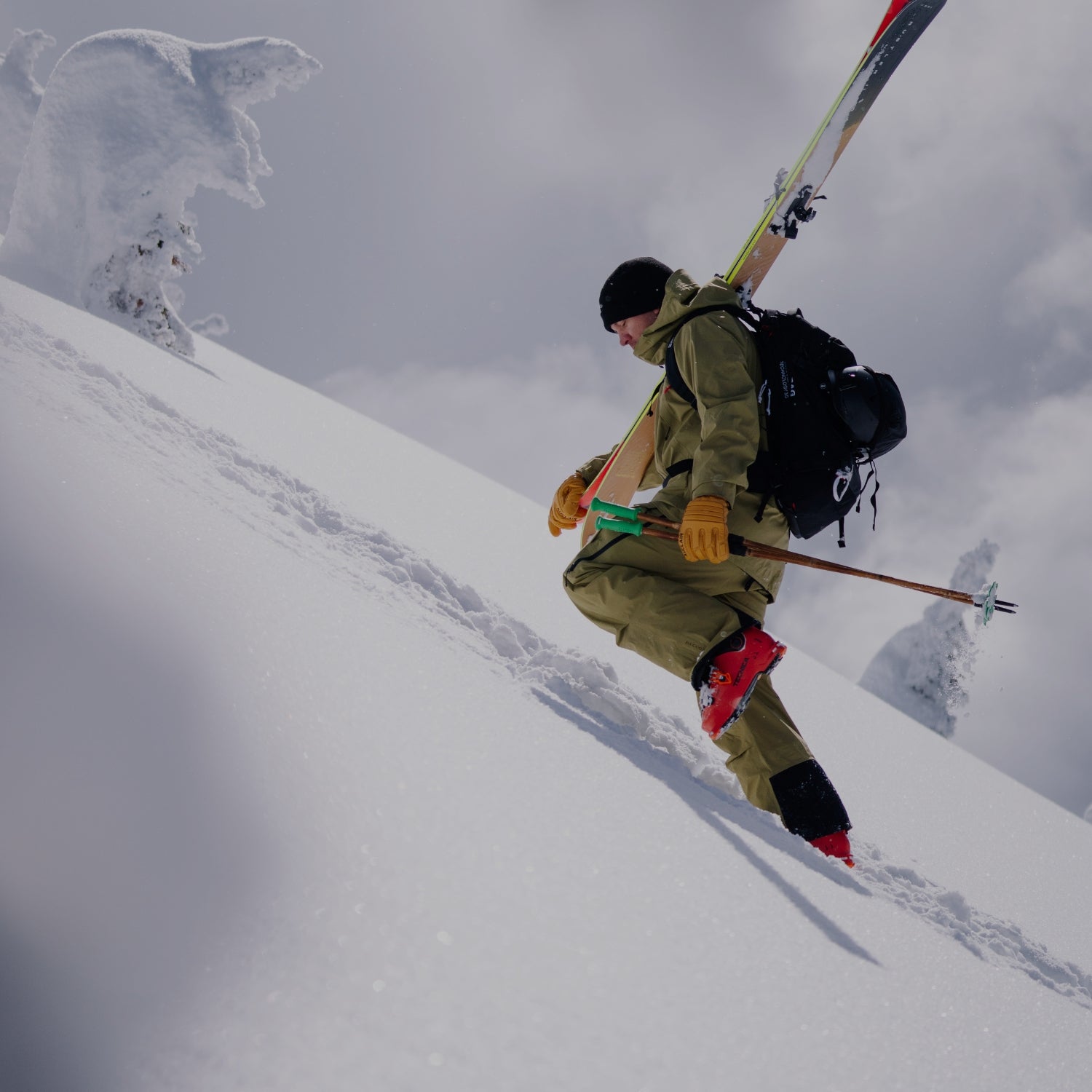 Skier with Auclair gloves climbing a pristine snowy slope, preparing for a backcountry descent.